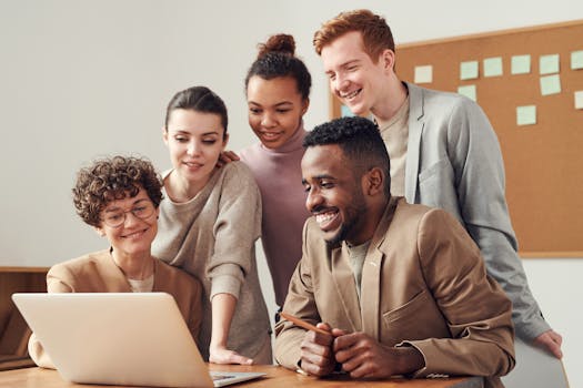 Inicio A group of diverse young professionals happily collaborating around a laptop indoors.